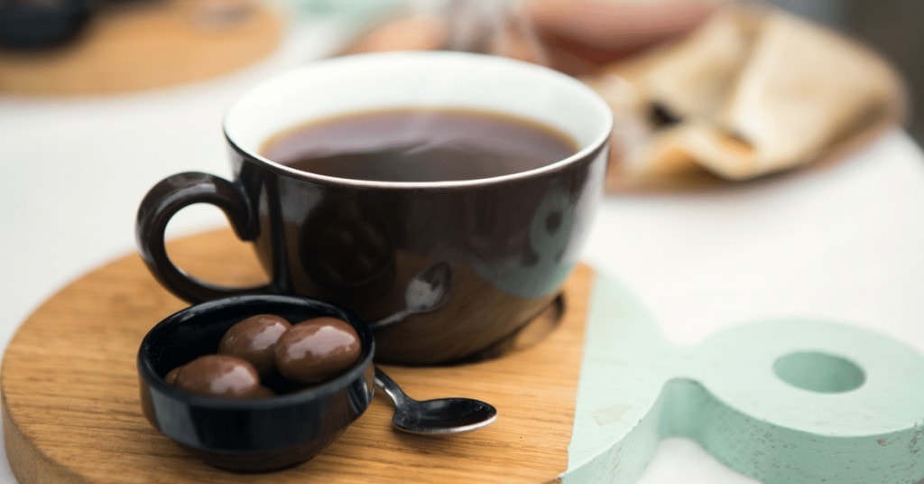 cup of black coffee and chocolate covered coffee beans