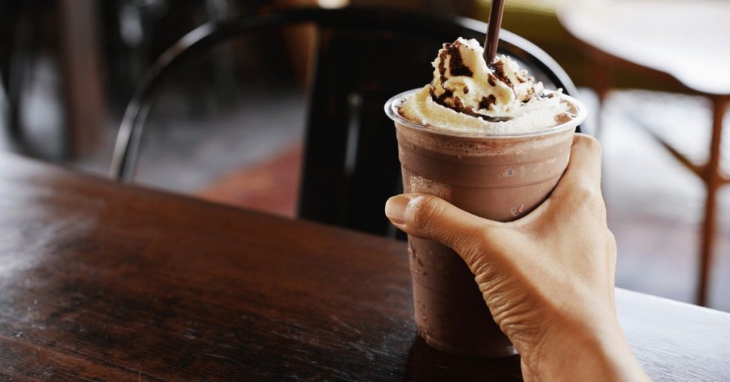 person holding a frappuccino with whipped cream