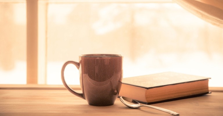 coffee mug and a spoon next to a book