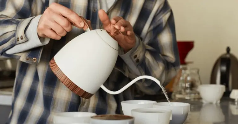 man pouring water from a white gooseneck kettle