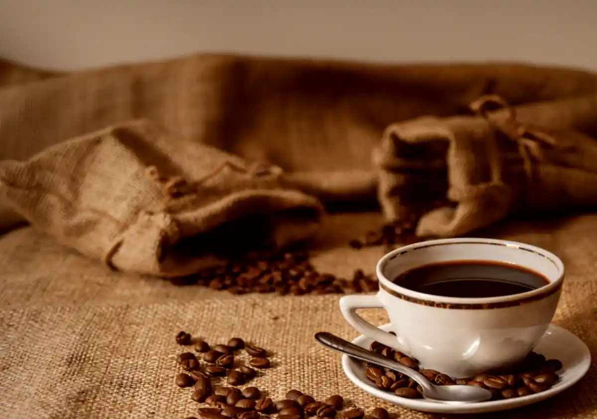 Cup of coffee surrounded by roasted coffee beans