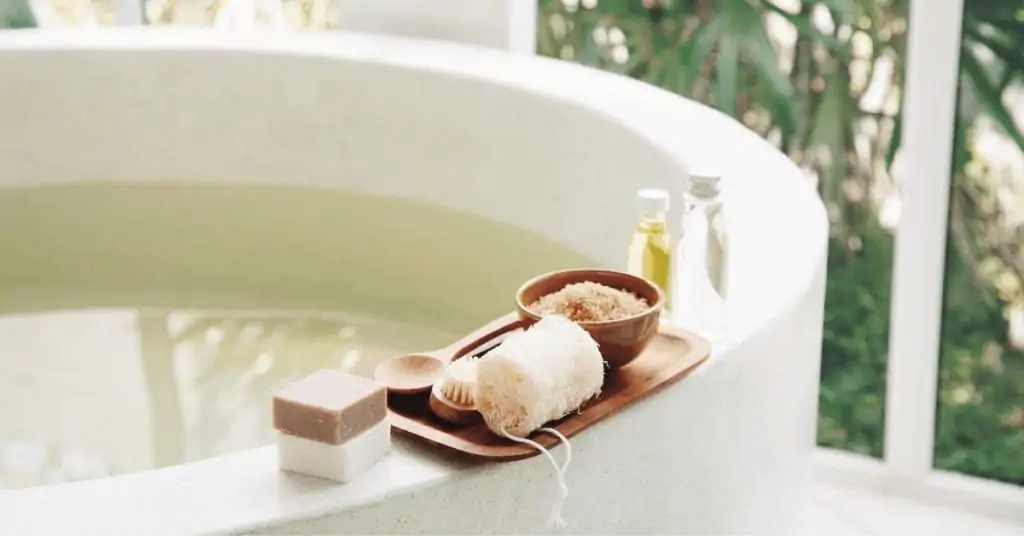 a full bath tub with epsom salts and soaps next to it