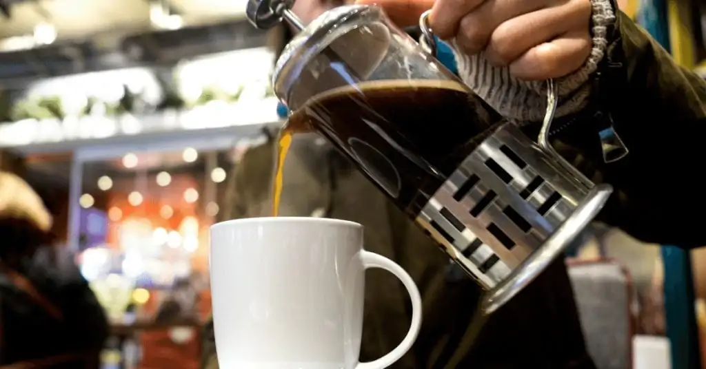 coffee being poured from a french press into a mug