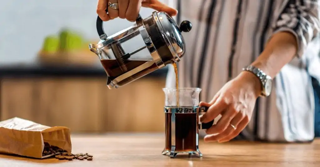 coffee being poured from french press into mug