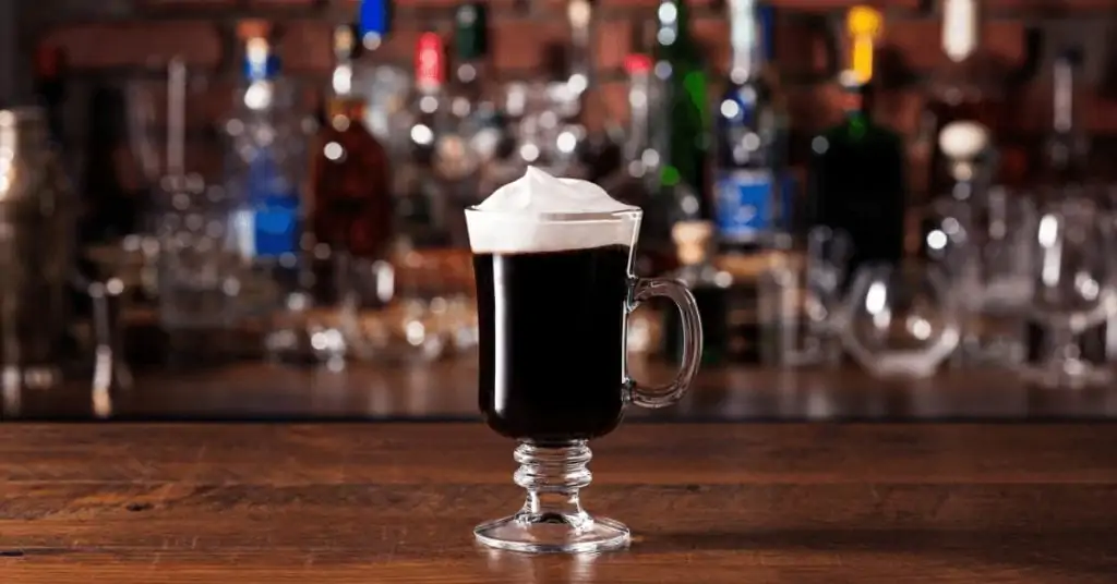 irish coffee on bar with alcohol bottles in background