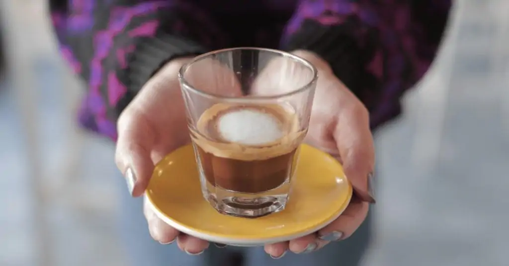 woman holding a macchiato on a saucer