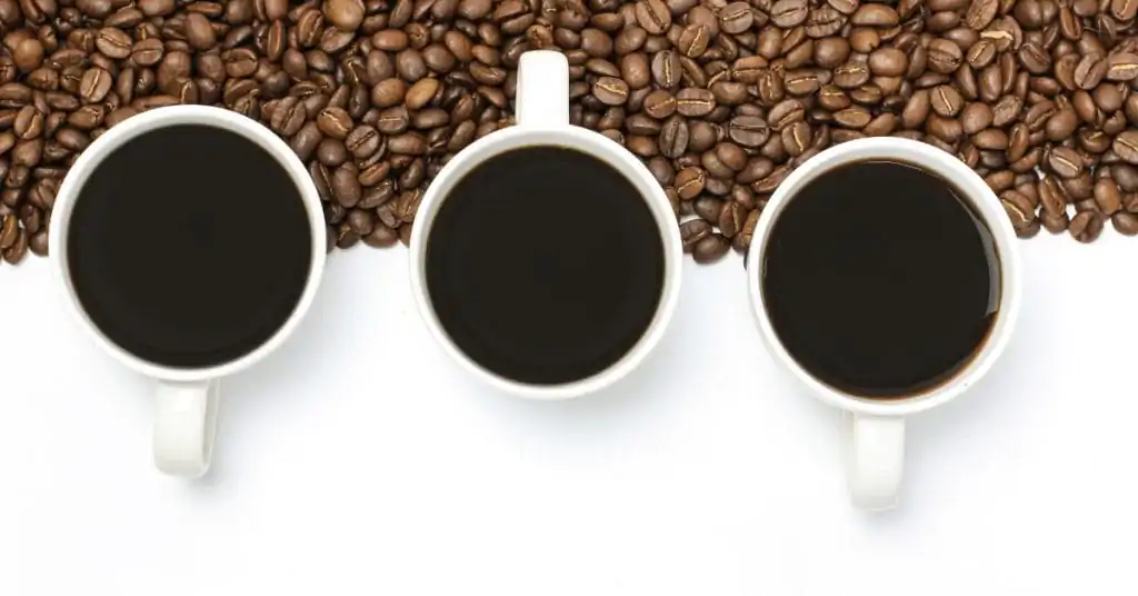 whole coffee beans and three cups of black coffee