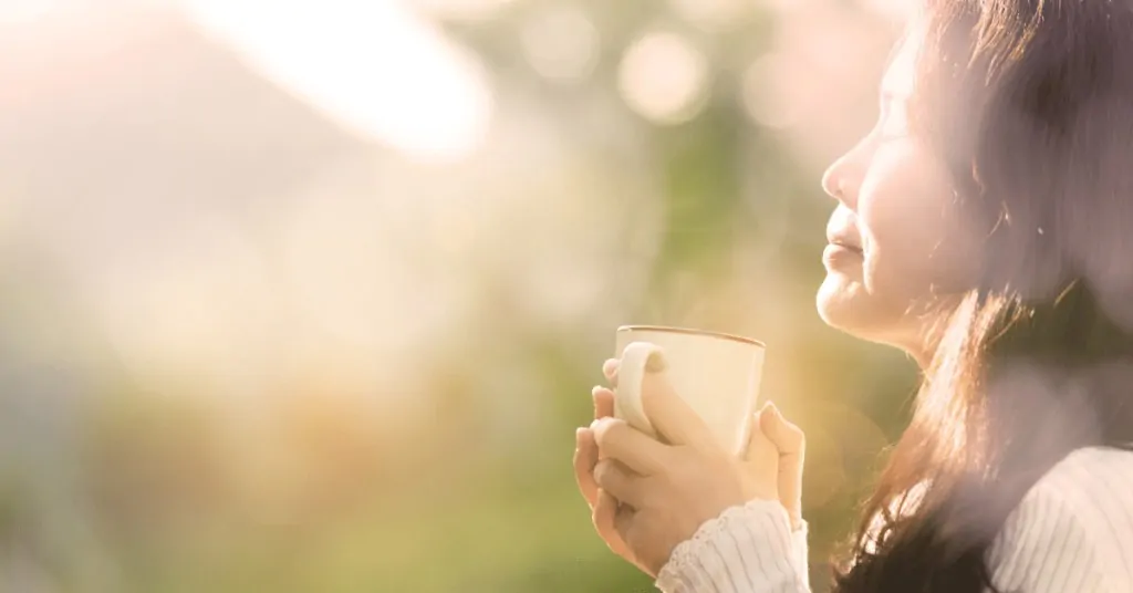 woman enjoying a cup of coffee outside in the sun