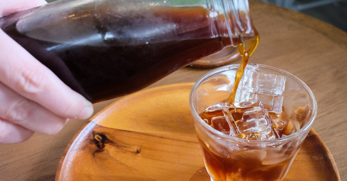 a person pouring cold brew coffee in a glass