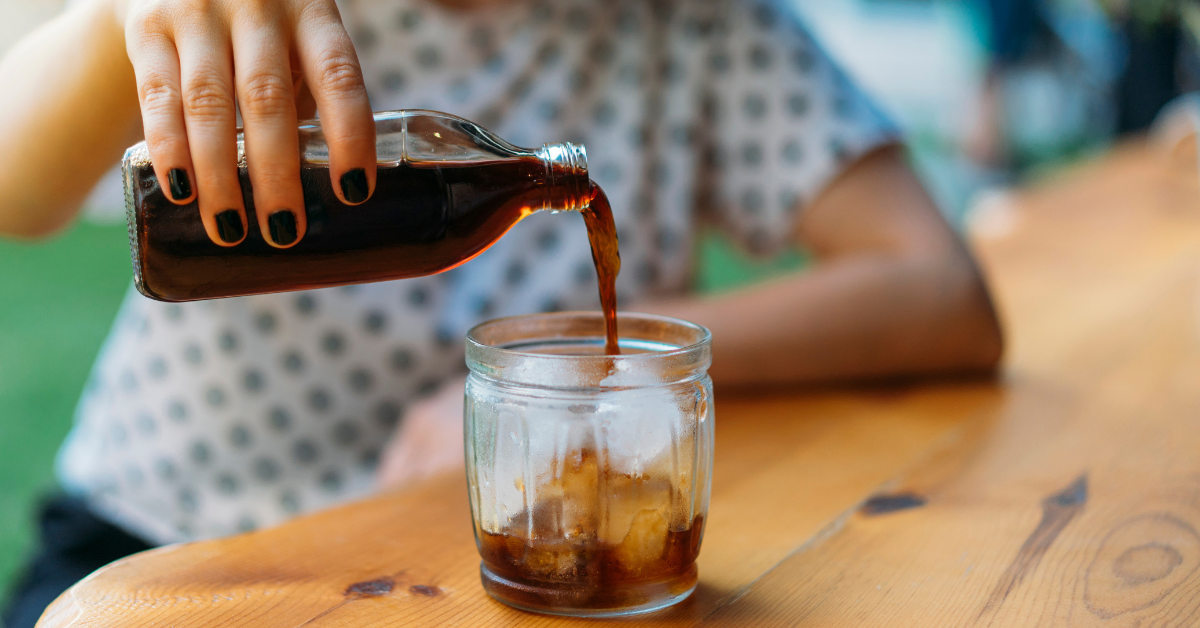 woman pouring cold brew coffee in a clear glass