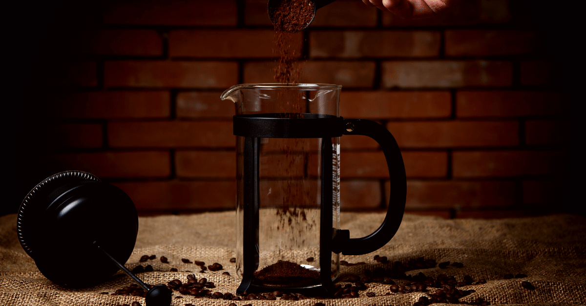 pouring ground coffee into french press