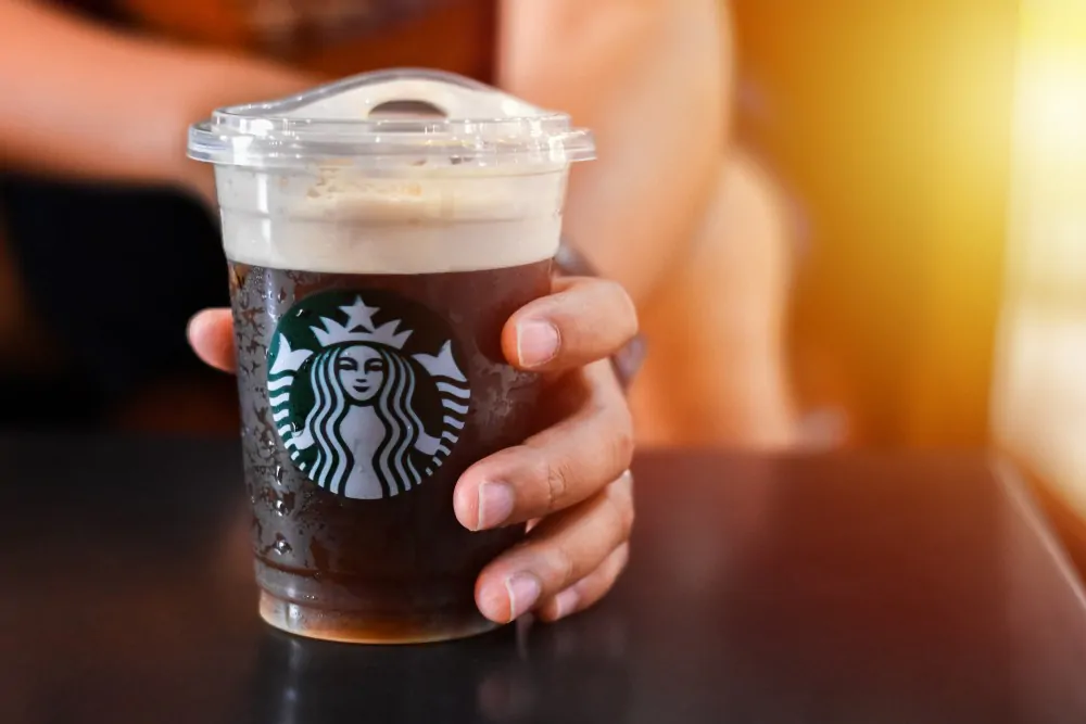 Man holding a Starbucks cold brew beverage cup in hand.