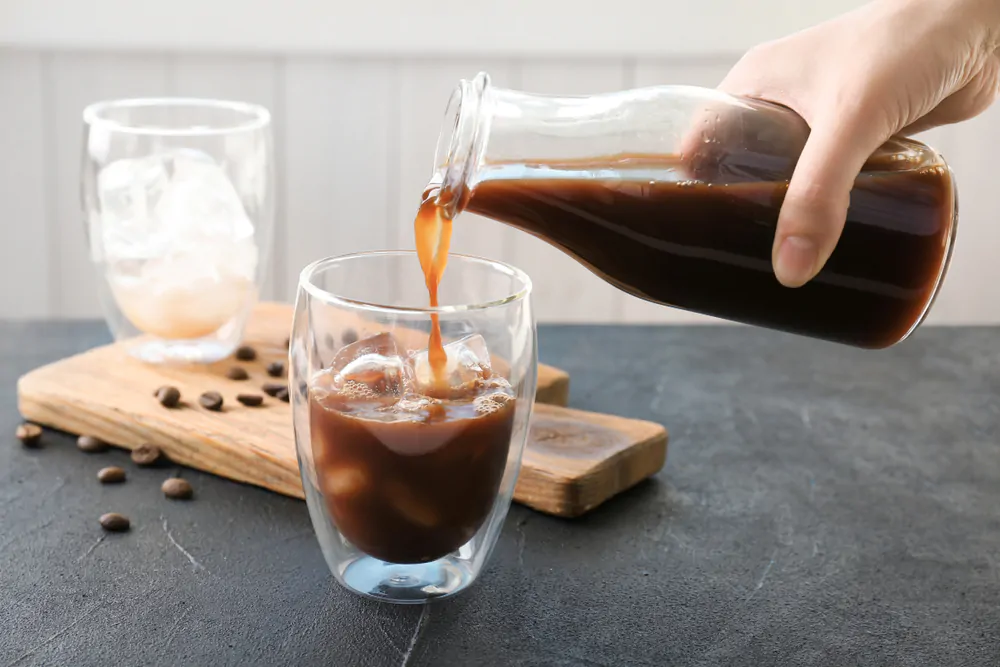 woman pouring cold brew coffee into glass