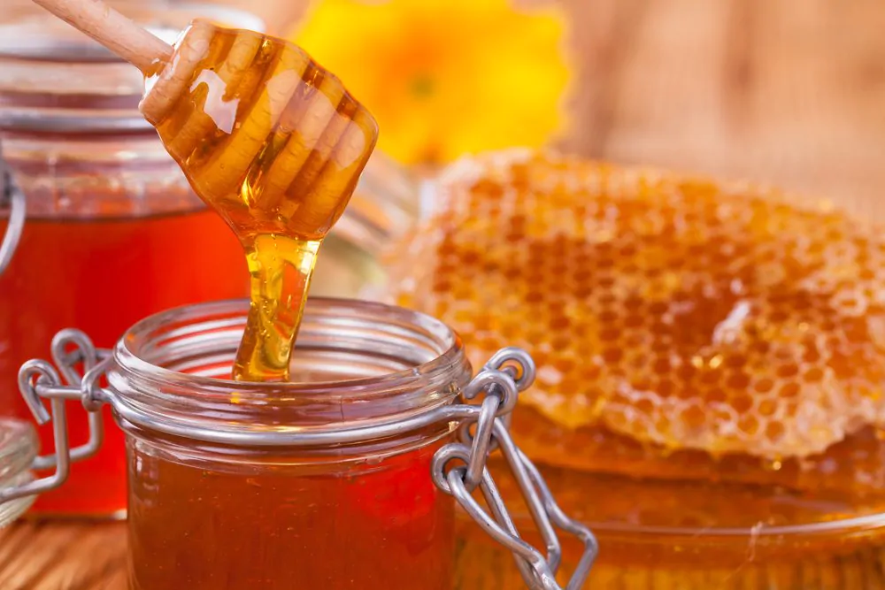 Honey in jar with honeycomb and wooden drizzler