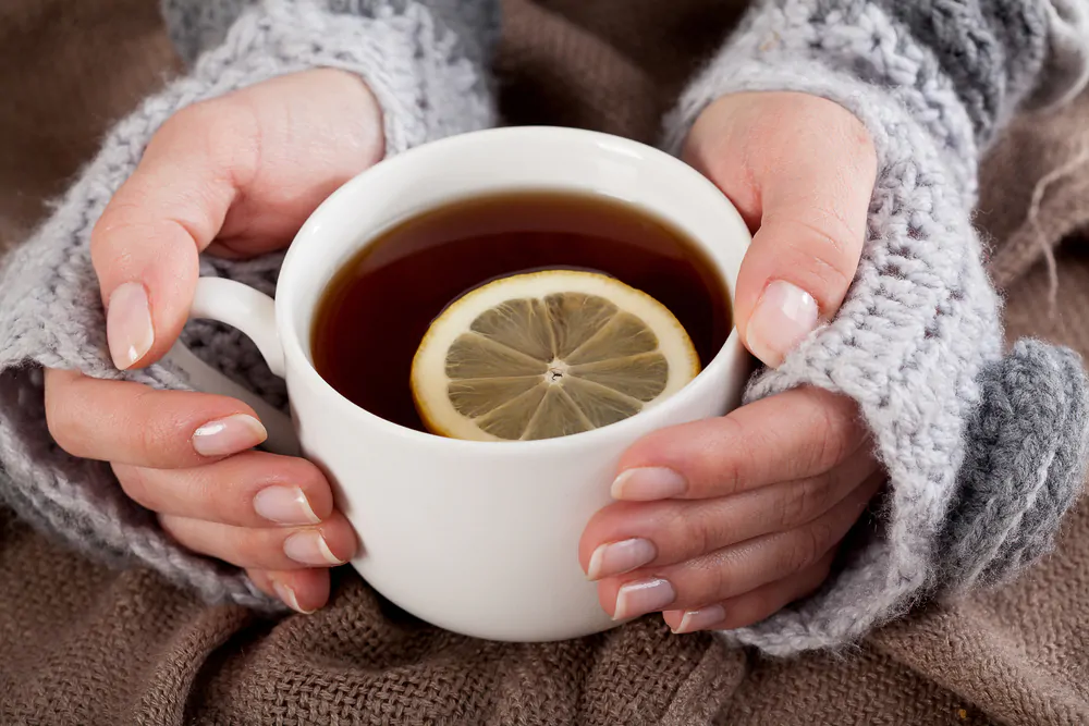 woman holding cup of tea with lemon